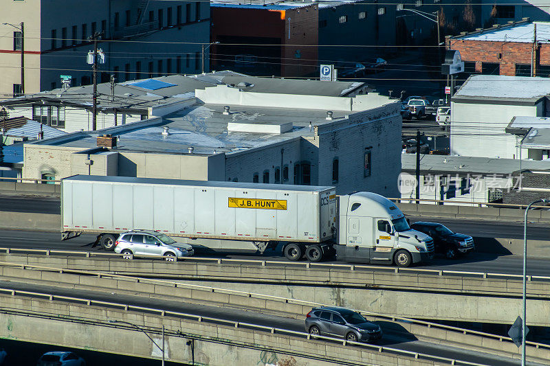 JB Hunt运输，专用合同服务部，在90号州际公路上驾驶半卡车穿过市中心。